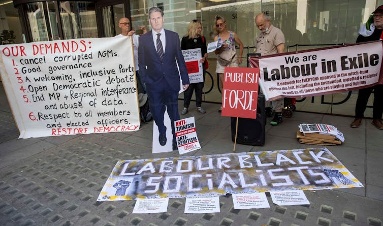 Protestors hold up signs criticising Labour leader Keir Starmer