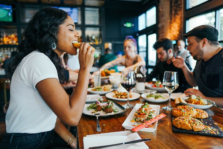 A woman eats at a table in a restaurant with friends