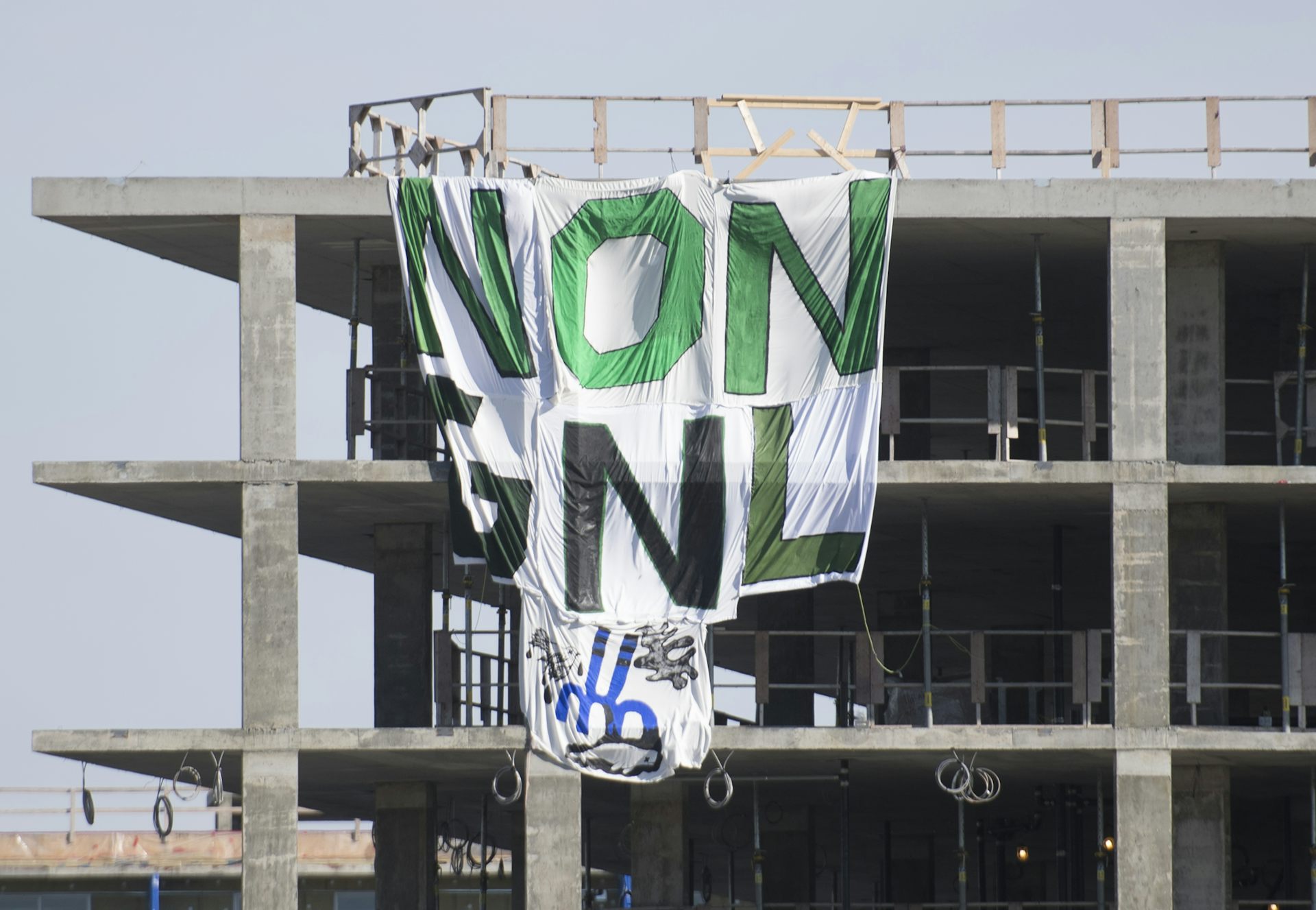 A Greenpeace banner reading ’No GNL’ is shown hanging from a building under construction.