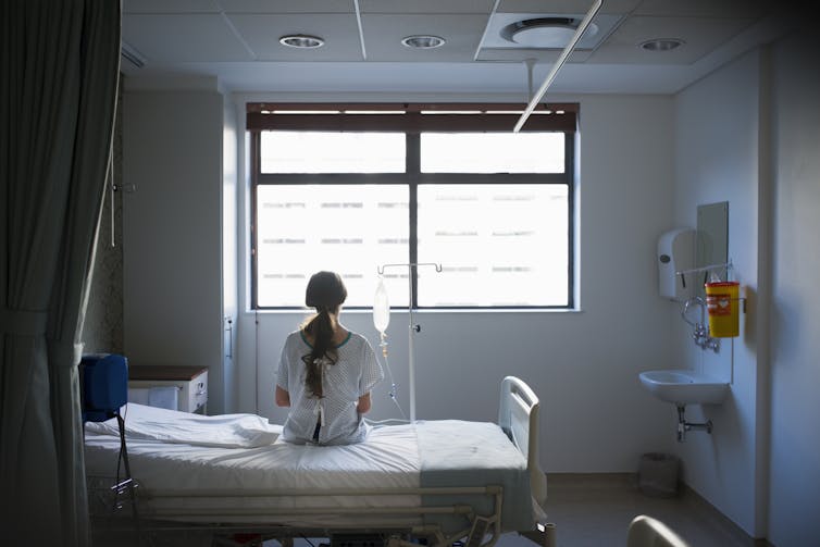 Patient sitting on hospital bed looking out window