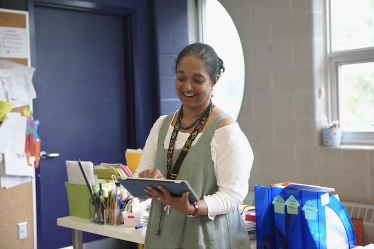 Teacher holds tablet while working in classroom