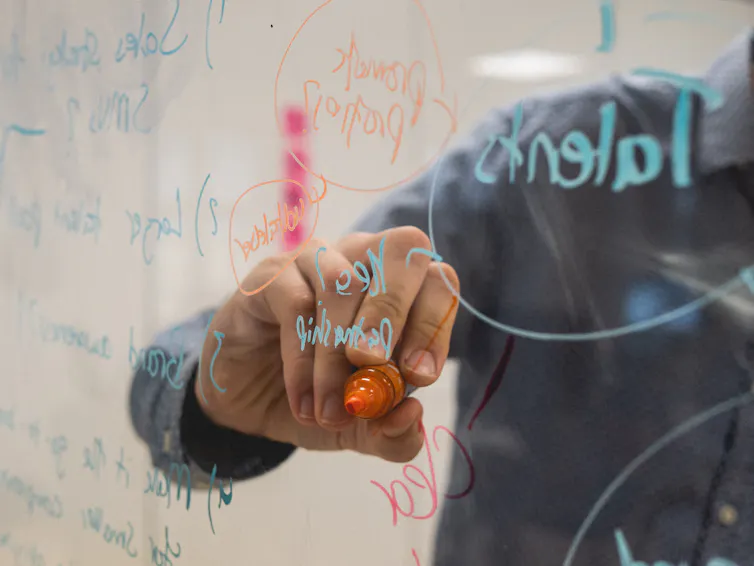 Writing on a clear whiteboard.