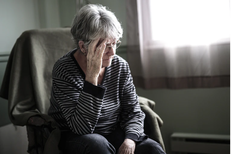 older woman sits and looks worried