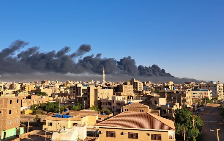 A city with smoke rising from semi high-rise buildings.