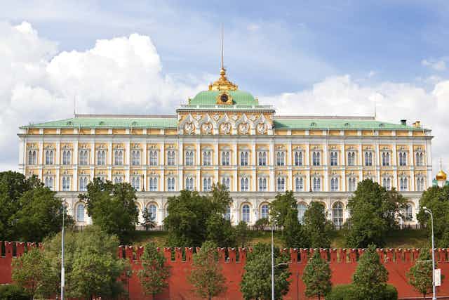 The facade of the Kremlin palace, with trees in front of it.