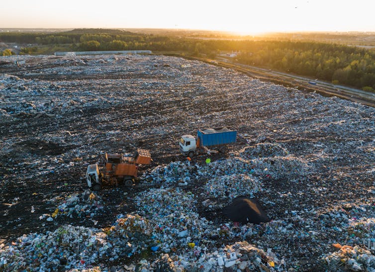 An aerial view of a landfill with two rubbish trucks.