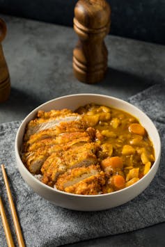 A bowl of chicken covered in katsu curry sauce.