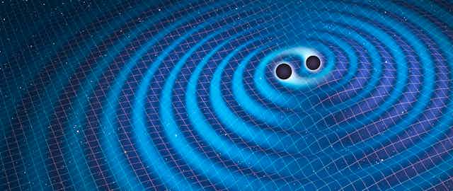 Two dark spheres in the center of ripples on a surface.