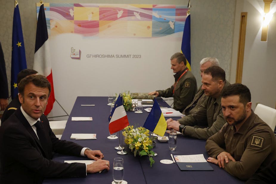 Volodymyr Zelensky, Emmanuel Macron et des membres de leurs délégations respectives autour d'une table au G7 d'Hiroshima