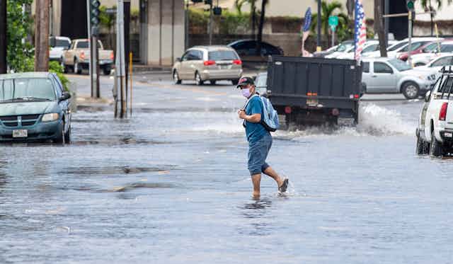 A person crosses a flooded road after a powerful storm.