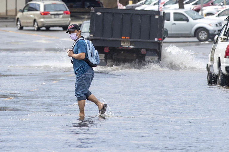 A person crosses a flooded road after a powerful storm.