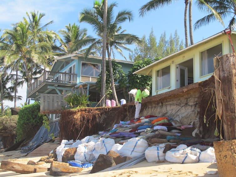 Sandbags sit outside a home near a beach in Oahu, Hawaii, where waves have eaten into the shoreline almost up to the house.