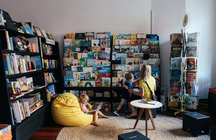 A mother looks at library books with her young son and daughter