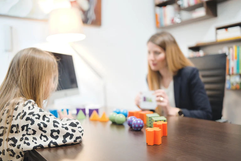 young person across desk from clinician and colourful shapes