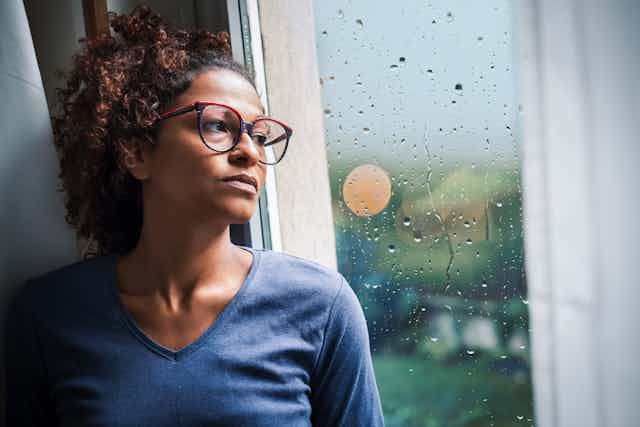 Woman stares out window at rain