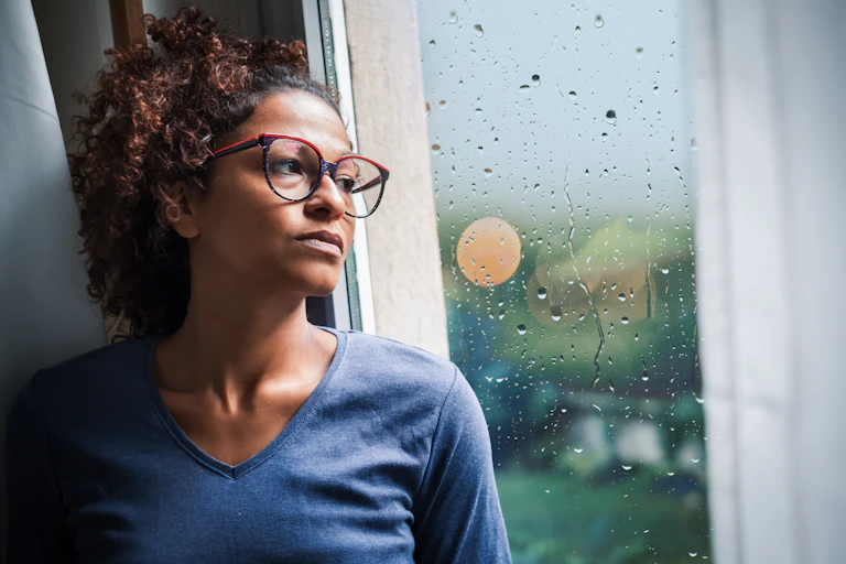 Woman stares out window at rain