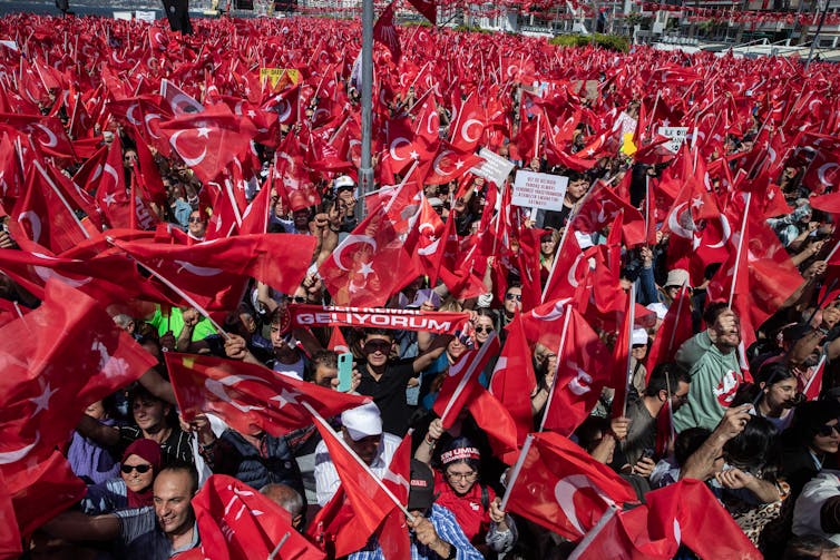 A huge crowd, with many carrying red flags.