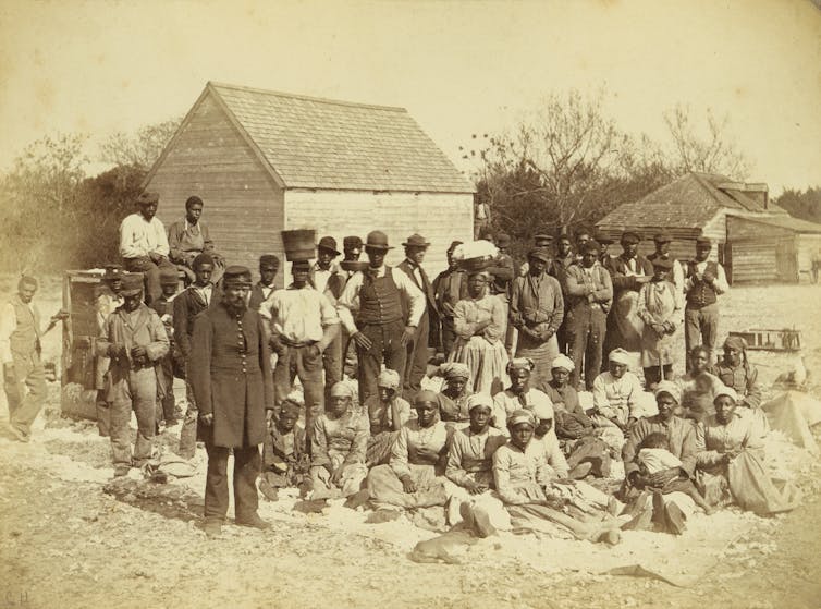 1862 photo of enslaved people and soldiers on a plantation, standing for the camera.