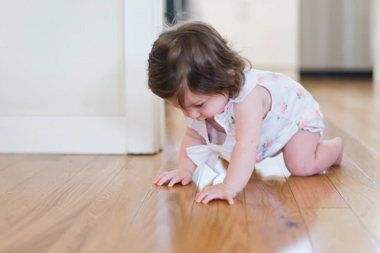 infant girl crawling on floor
