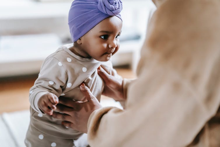 baby learning to walk is supported by adult