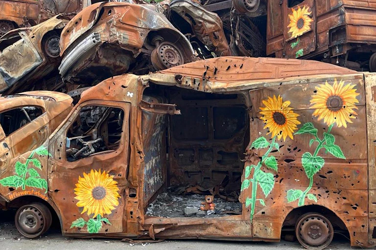 Van détruit et criblé de balles, couvert de dessins représentant des tournesols
