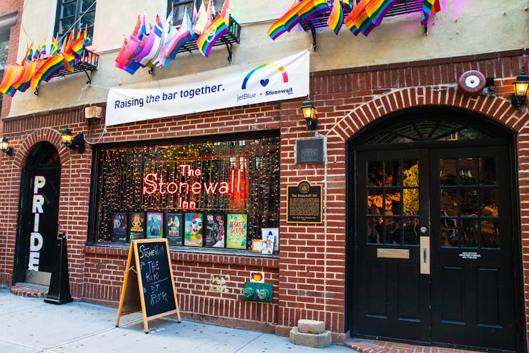 The outside of the Stonewall Inn bar with pride flags and red brick walls.