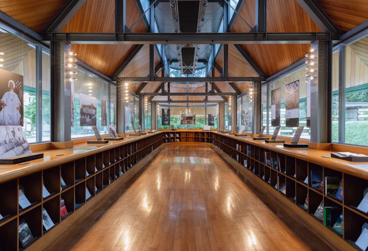 A room with wooden floor and wooden shelves displaying books and with photographs displayed all the way around it.