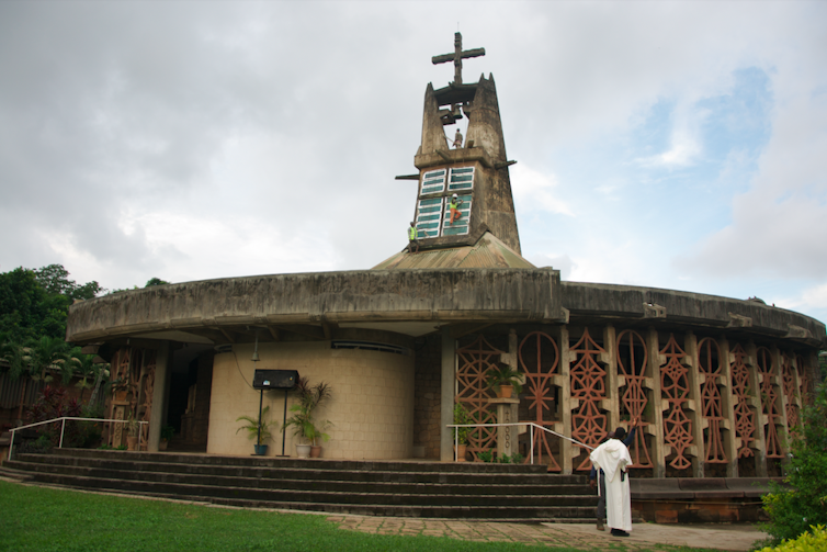 A round church like structure with a rustic spire and ornamental detail of African symbols.