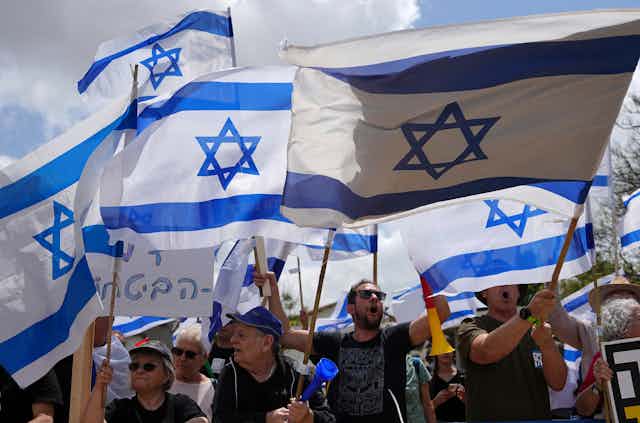 People at a protest wave Israeli flags.