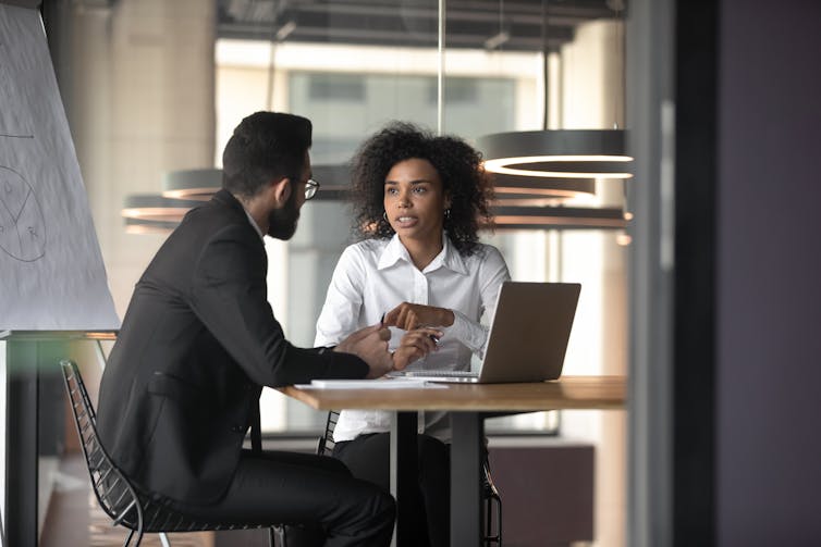 A man and a woman having a discussion while seated at a table.