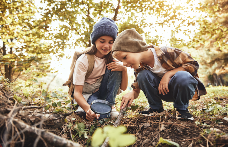 Children looking at things in the garden with a magnifying glass