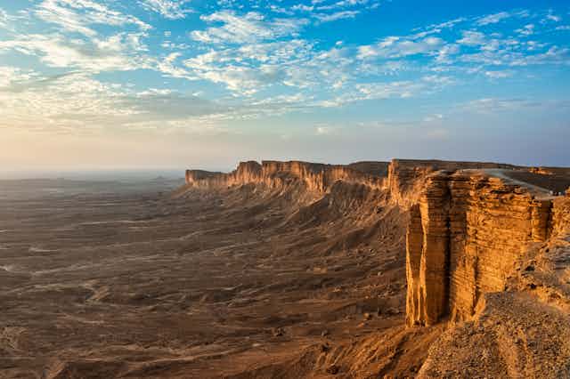 A photo of rocky cliffs above a sweeping landscape in Saudi Arabia.
