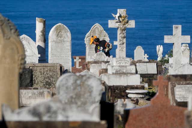 a gardener at work among headstones in a cemetery in Sydney