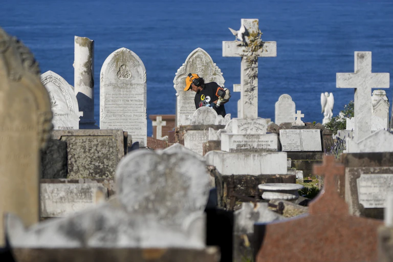 a gardener at work among headstones in a cemetery in Sydney