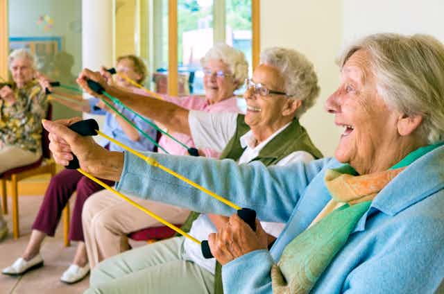 Elderly women sitting doing arm strengthening exercises