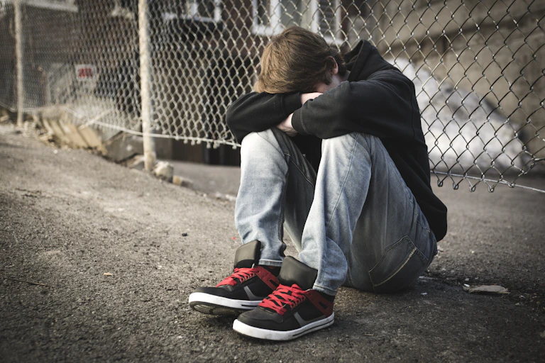 Sad child sitting on the side of the road,