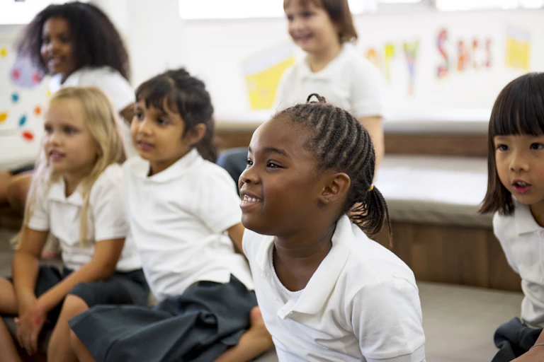 Group of children wearing school uniform sat on floor