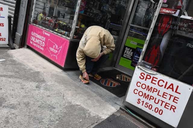 A man wearing a hoody bent double in a shop doorway