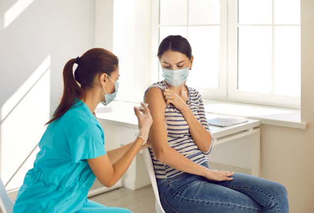 A woman receives a vaccination from a healthcare worker.
