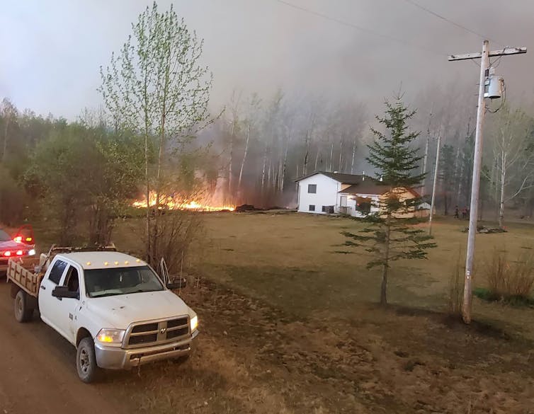 Fire and smoke is seen close to a house.