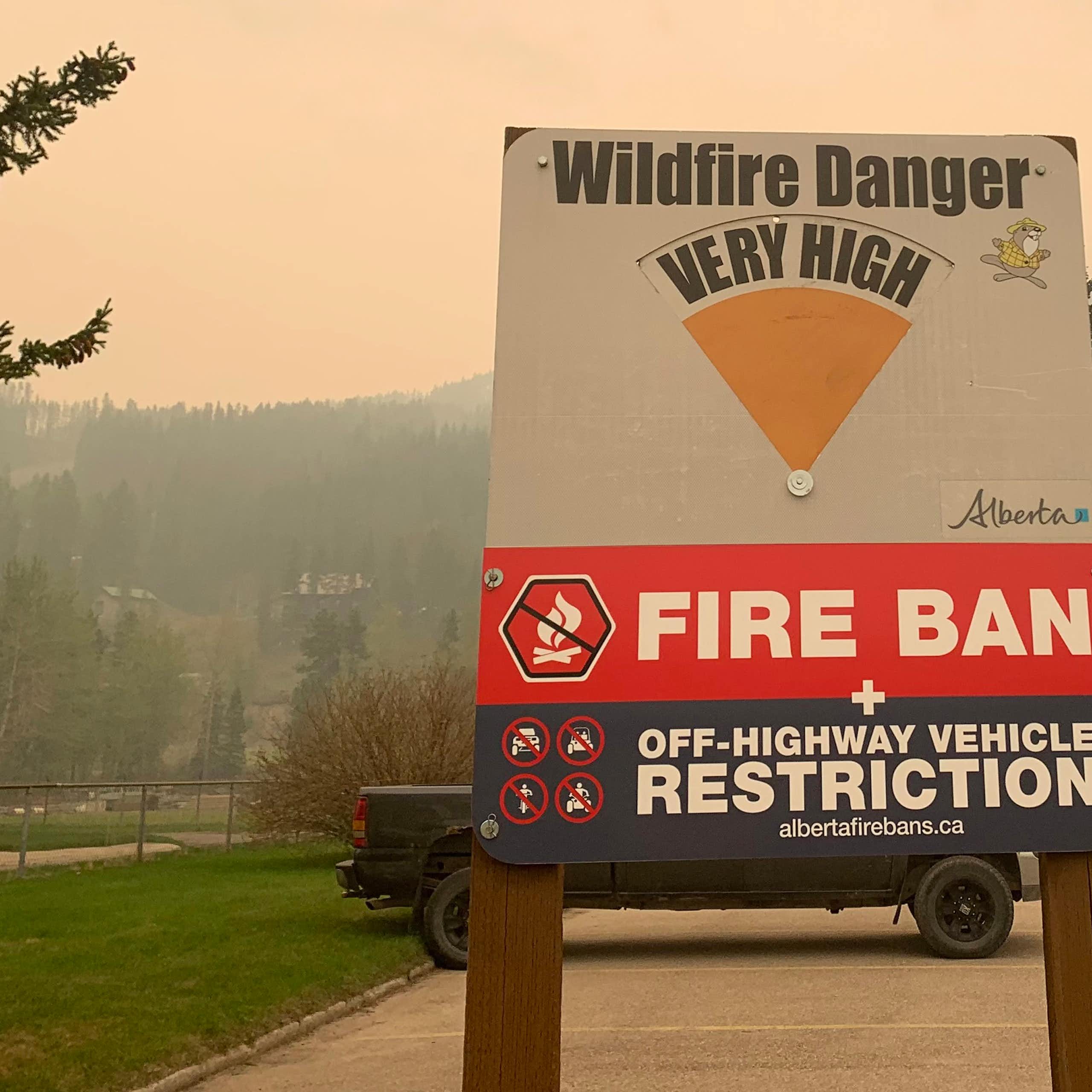 A wildfire danger sign seen with the words "fire ban" against a hazy sky.