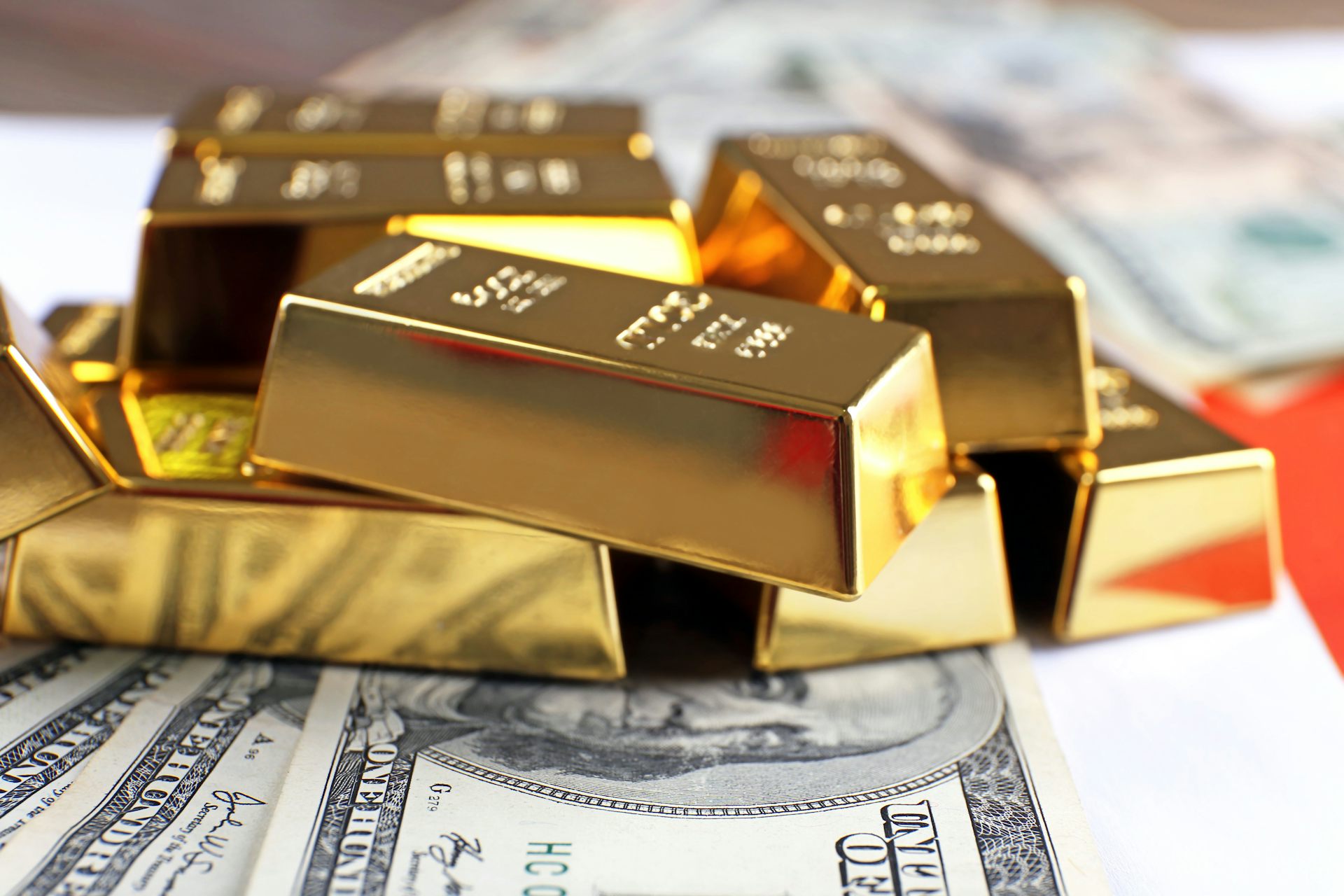 An image of several gold bars lying on top of US dollar notes