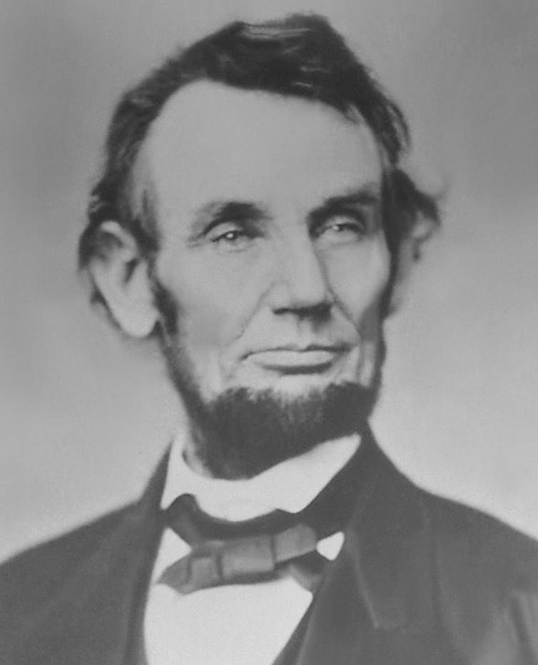 Dressed in a three-piece suit, Abraham Lincoln sits for a photograph.