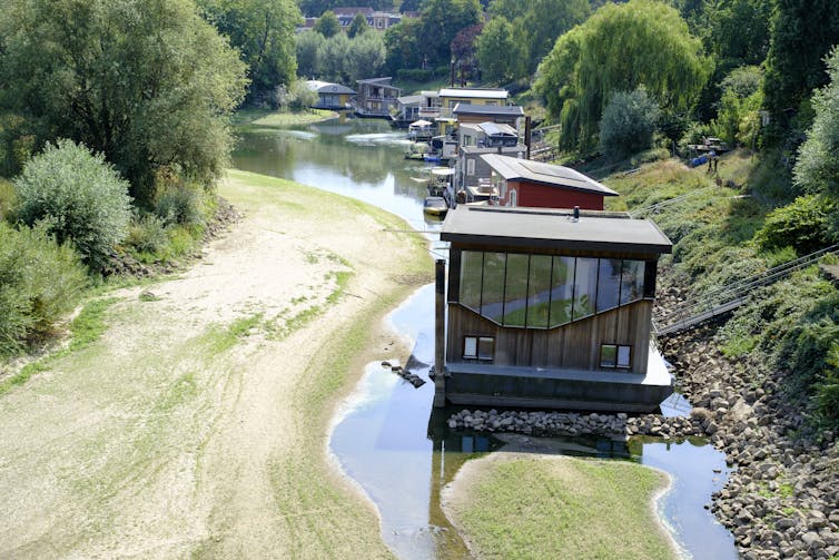 A line of houseboats that once floated on a river sit in puddles on the nearly dry riverbed during a flash drought.