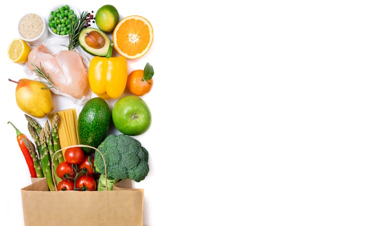 A shopping bag with fruit, vegetables and other fresh groceries spilling out
