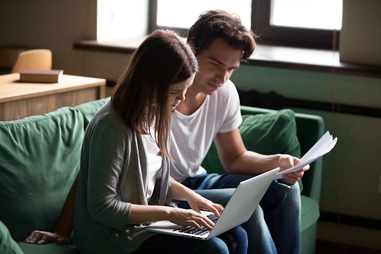 young woman and man look at papers and laptop