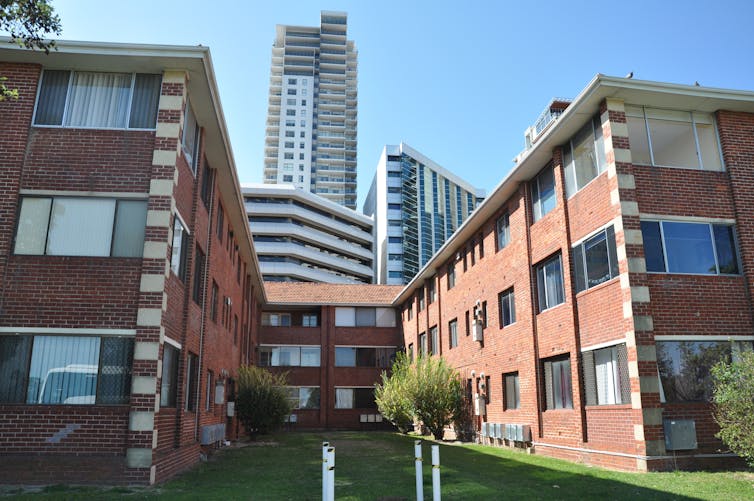 older-style apartment block in front of high rises