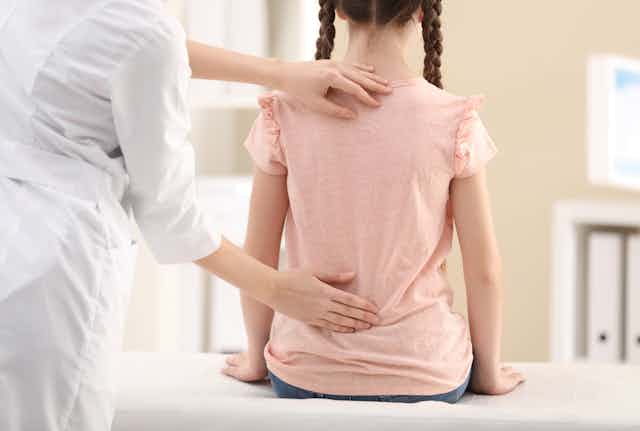 Une médecin regarde le dos d'une petite fille