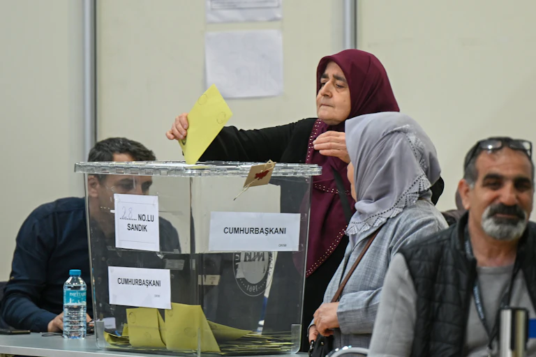 Une femme voilée dépose un bulletin dans une urne