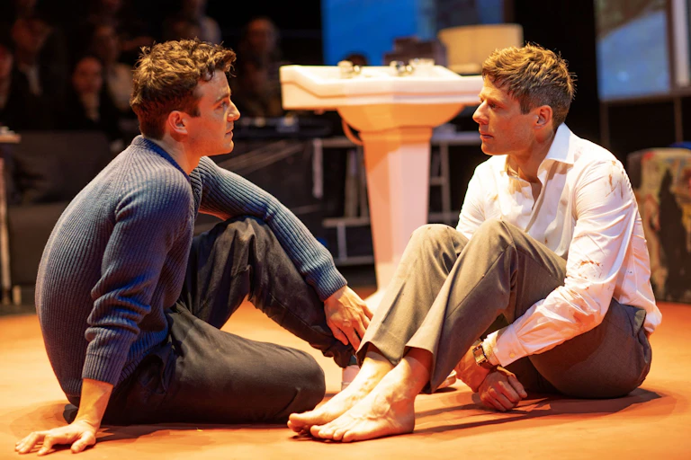 Two men sit on the floor with each other.